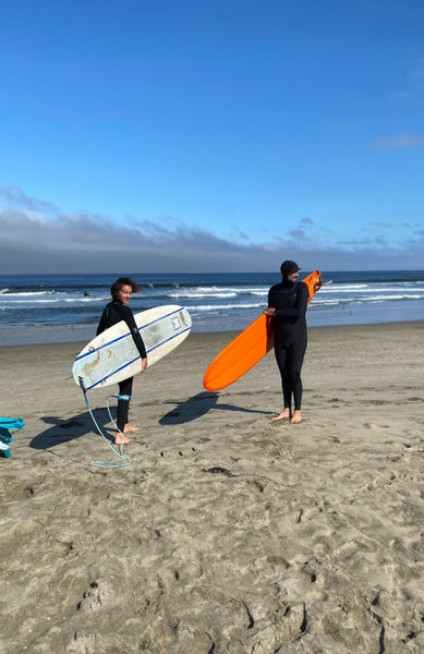 Dave and his daughter walking towards the surf on a beach.