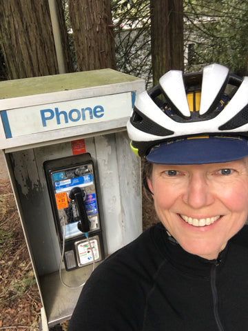 Selfie of Lynell with a telephone booth in the woods behind her.