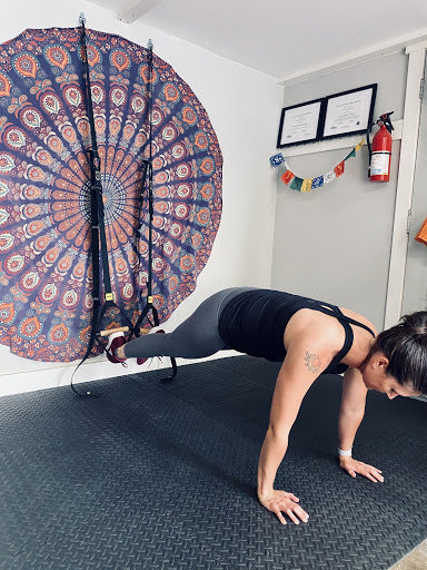 Jaimie doing a push up with her legs in the TRX loops.