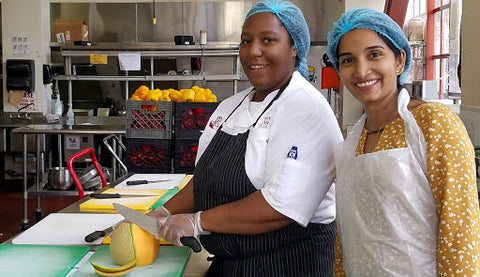 Two people helping in a kitchen.