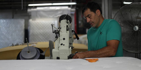 Man tape edging mattress in New York factory