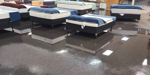 Flooding inside the mattress store with water around the mattresses.
