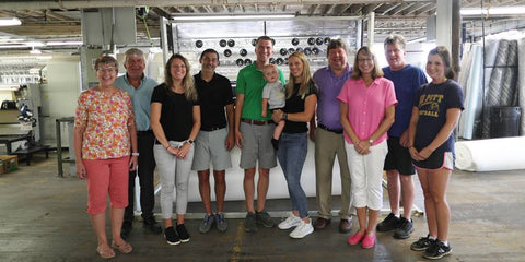 Family in front of quilting machine inside their New York Manufacturing Facility