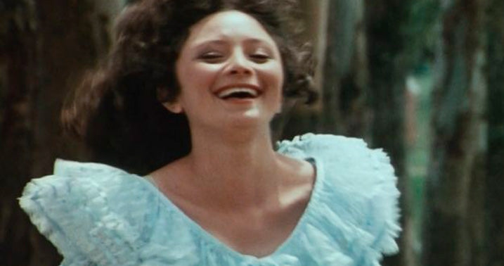 foto de busto de uma mulher sorrindo com um vestido de babados em cena do filme a hora da estrela