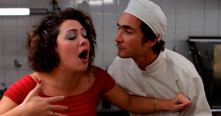 mulher engasgada enquanto cozinheiro a acode em cena do filme estomago