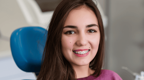 Young teenage girl in dental chair showing healthy teeth with braces