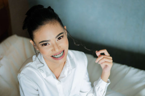 Young woman in white shirt showing a big beautiful smile with a mouth full of orthodontic braces