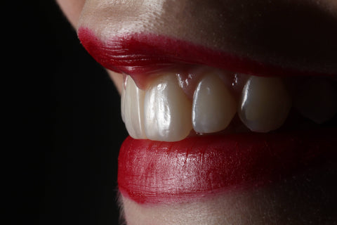 Closeup of female mouth wearing red lipstick showing beautiful white and healthy teeth