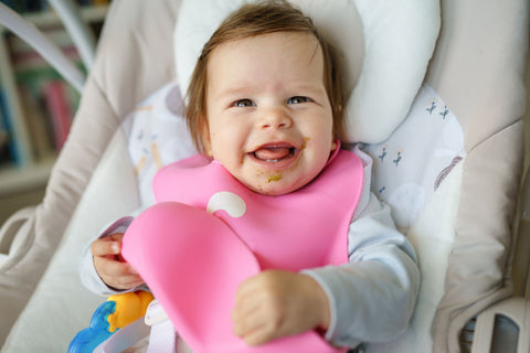 Laughing baby wearing a pink bib