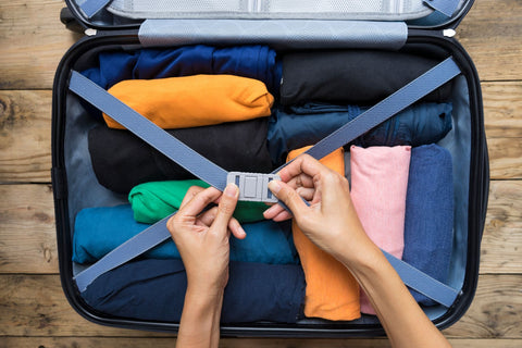 A person packing their suitcase by rolling their clothes