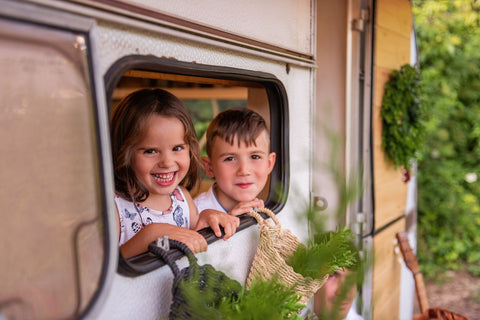 Two kids looking through the window of the caravan