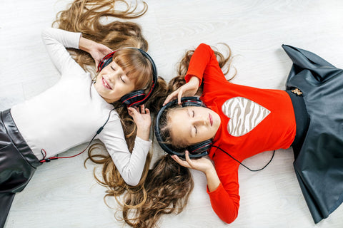 Two girls listening to music over headphones