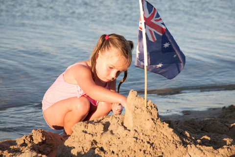 Boy adding an Australian flag to his sandcastle