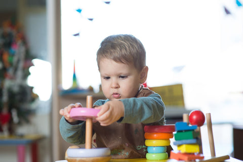 Boy playing with his wooden Montessori stacking toy