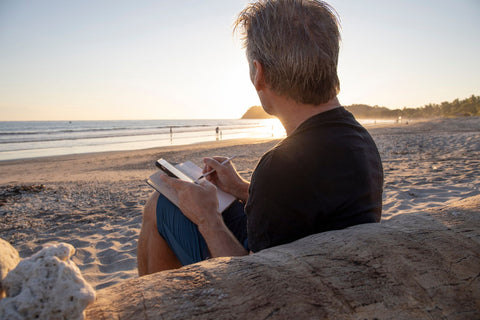 A man writing his travel journal while sitting on a beach in Australia