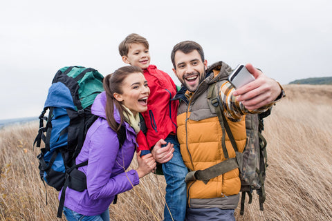 A family wearing rain jackets and hiking backpacks