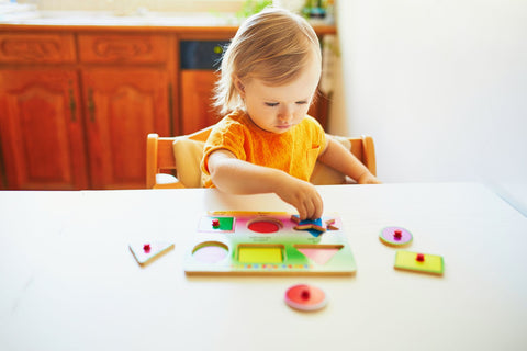 Toddler completing a wooden Montessori shapes puzzle