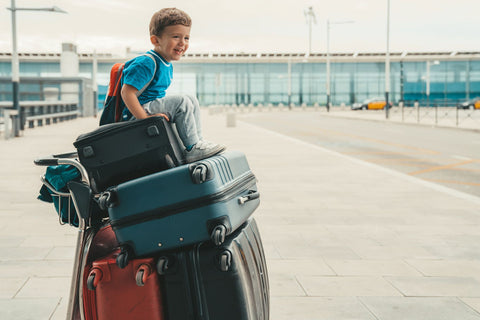 child sitting on the luggage trolley at the airport