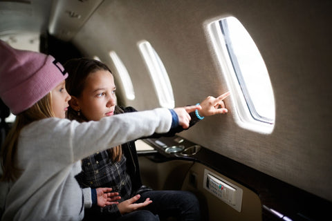 Two girls looking out of the window on an airplane