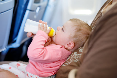 baby on dad's lap drinking from a bottle on a plane