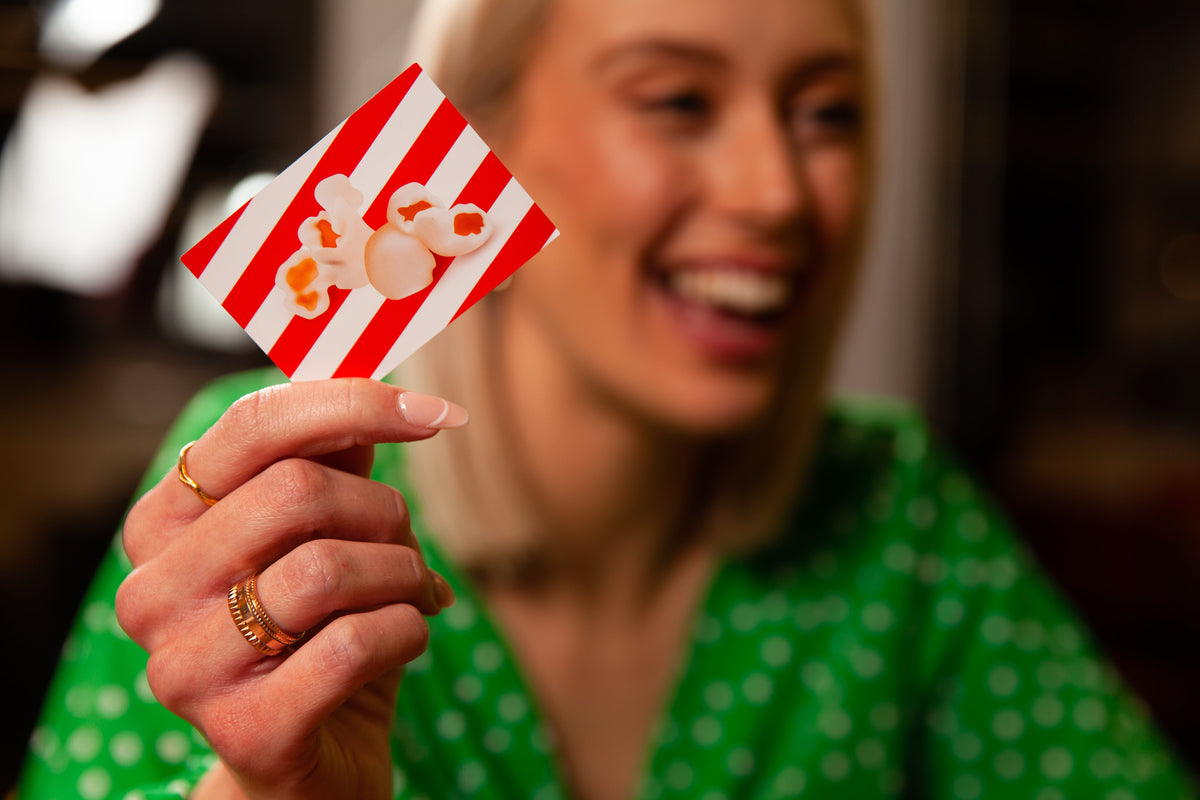 Woman holding red and white striped card with a popcorn picture on it