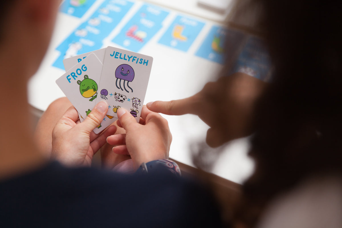 Looking over the shoulder of a person with a 'frog' and a 'jellyfish' card in their hands