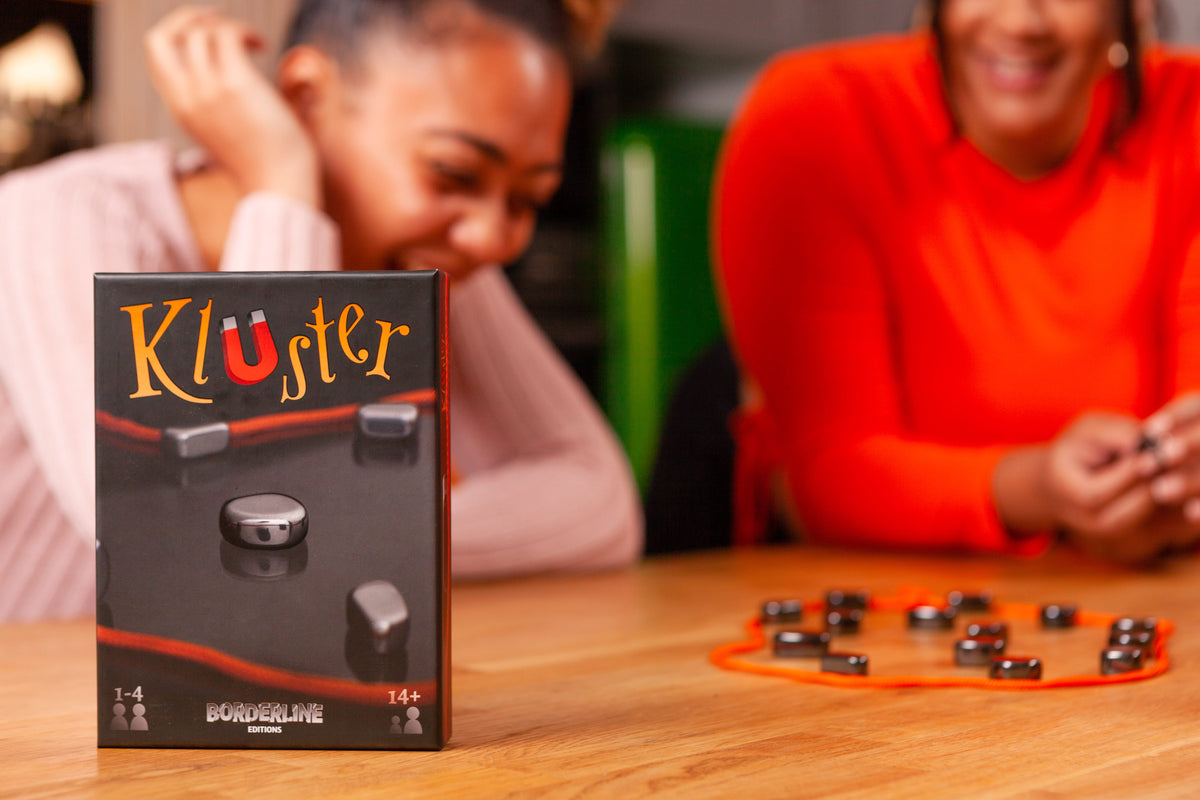 Kluster game box in front of two people playing