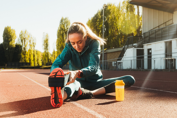 Eilish McColgan’s Top Ten Daily Stretching Exercises in the running track with her Zest Active Supplement in a shaker