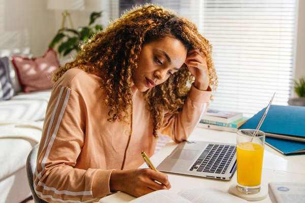 Top Tips For Exam Season: Eating For Success  lady sitting at her desk studying with a glass of Revive Active Supplement