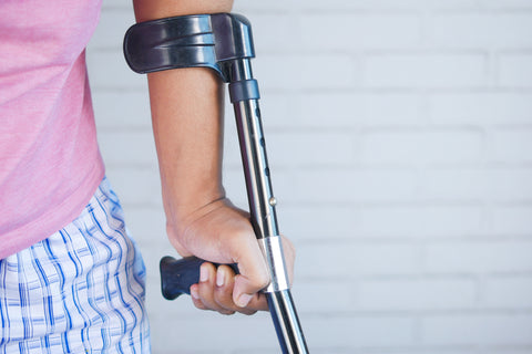 forearm crutch being used by a lady in a pink t-shirt and pyjamas