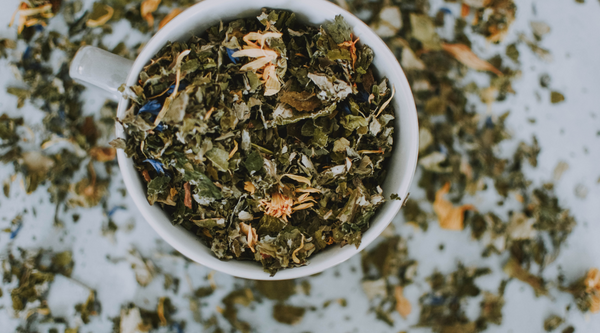 A cup filled with loose leaf herbal tea.