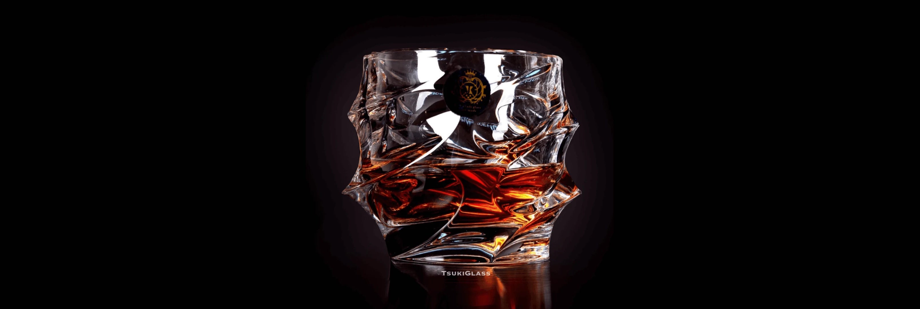 Crystal glass with amber liquid on a dark background.