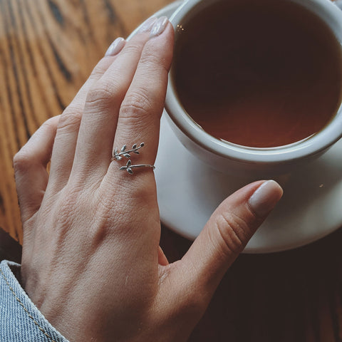 A feminine hand rests on a cup holding coffee. Photo by Valeriia Miller.