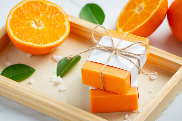Two scented soaps along with orange peices beautifully decorated in a wooden tray