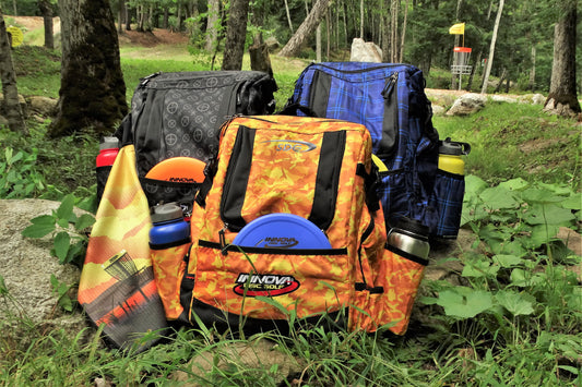 Three Innova Hero Pack Disc Golf Bags with accessories Sitting on the course at trainzwholesale 