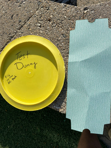 A yellow disc with sandpaper next to it on a stone patio.