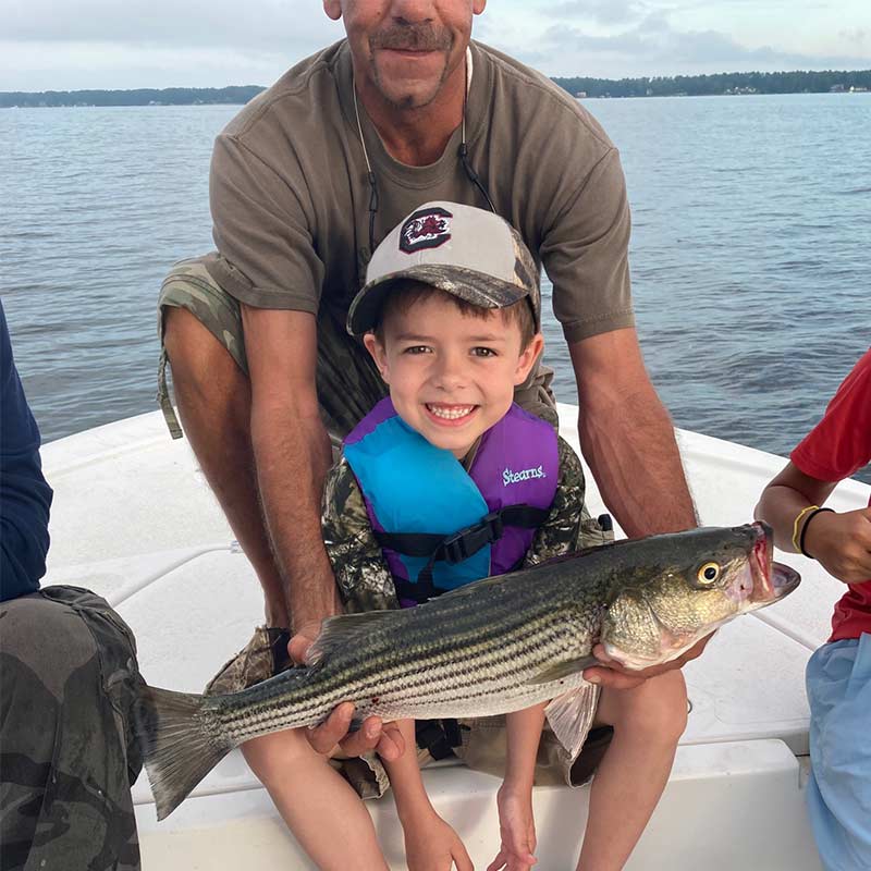 A young fellow thrilled to catch a nice striper with Captain Brad Taylor