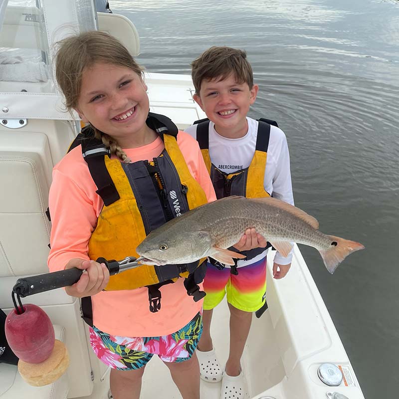 A pair of happy young anglers caught this redfish with Captain Smiley Fishing Charters