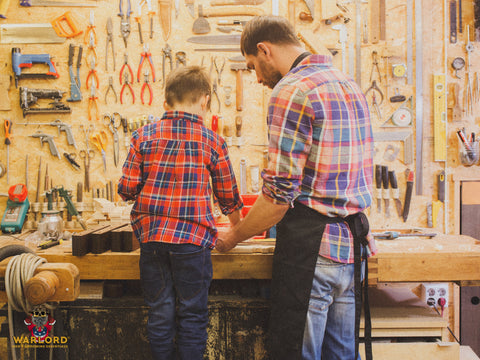 Father and little son with wood plank at workshop