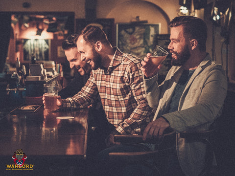 Cheerful old friends having fun and drinking draft beer at bar counter in pub.