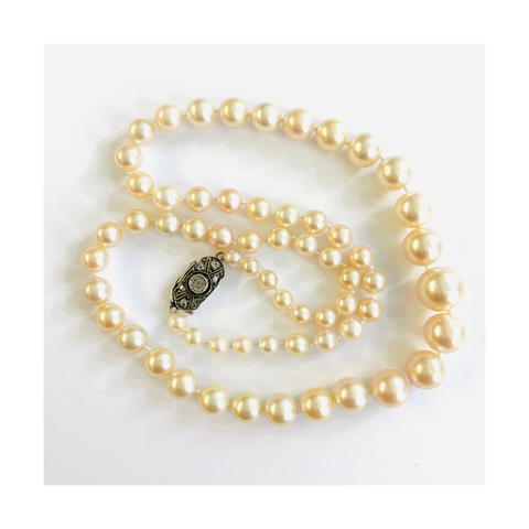 Natural pearl strand, showcases 63 pearls with a 14-karat gold clasp adorned with an old mine diamond.
