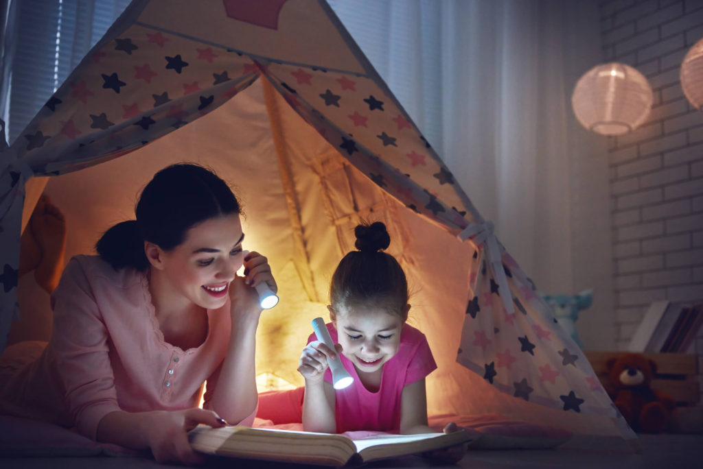 mom and daughter reading in tent