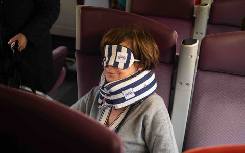 Femme qui dort dans le train avec un soutien cervical parfait grâce au coussin de voyage Le Petit Dormeur