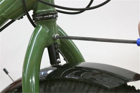 A mechanic uses a screwdriver on the fork of a bike to install a fender flute