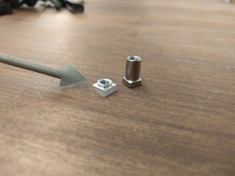 A small nut and bolt sit on a wood tabletop