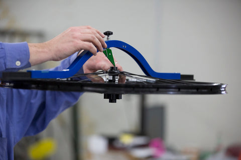 A mechanic uses a wheel dishing gauge on a wheel.