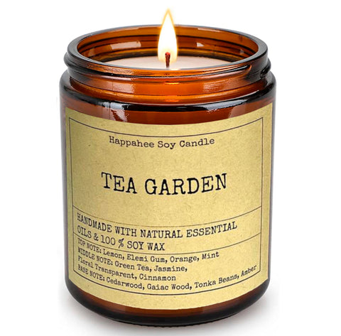 The Tea Garden scented candle from Happahee, alight in an amber jar with a sticker, on a white background, capturing the soothing harmony of tea and nature, a serene addition to any Dubai residence.