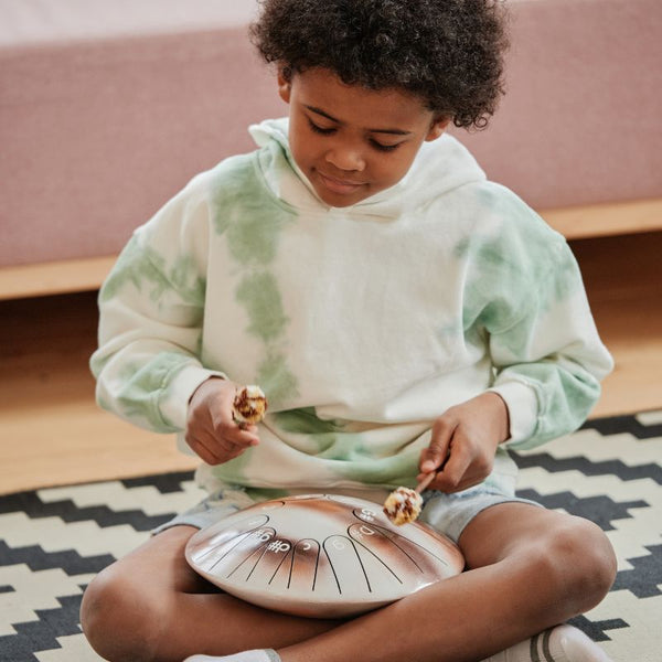 un enfant joue du tongue drum