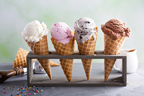 4 different ice cream cones resting on a cone rack. Yum.