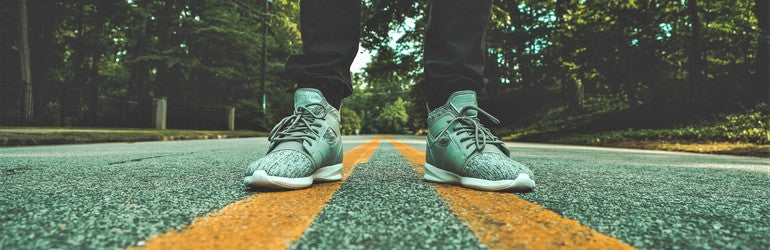 A person stands on a road contemplating the challenge ahead.